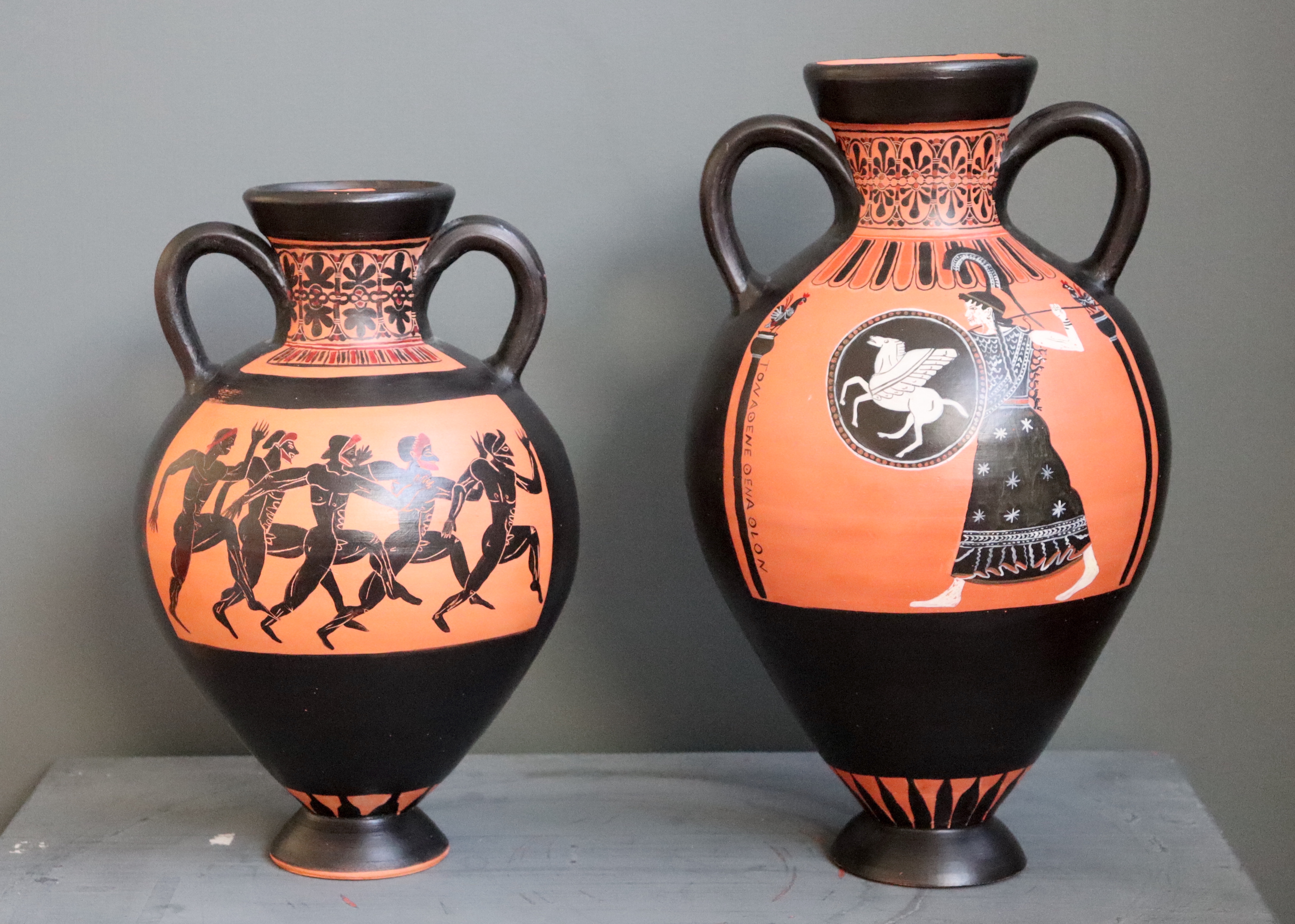Two replica Panathenaic vases, one with Athena and one with a running race