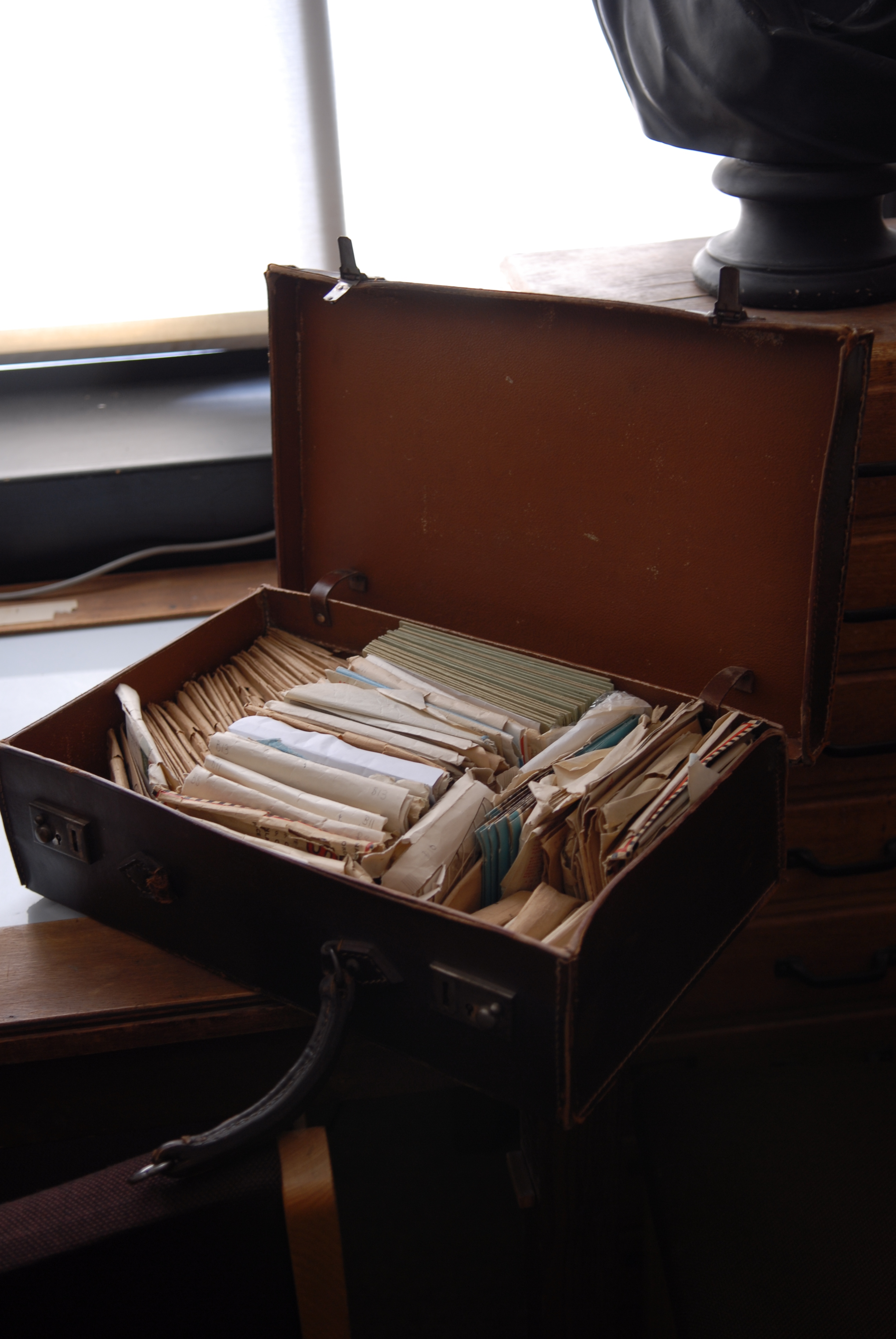 an open brown leather suitcase filled with envelopes