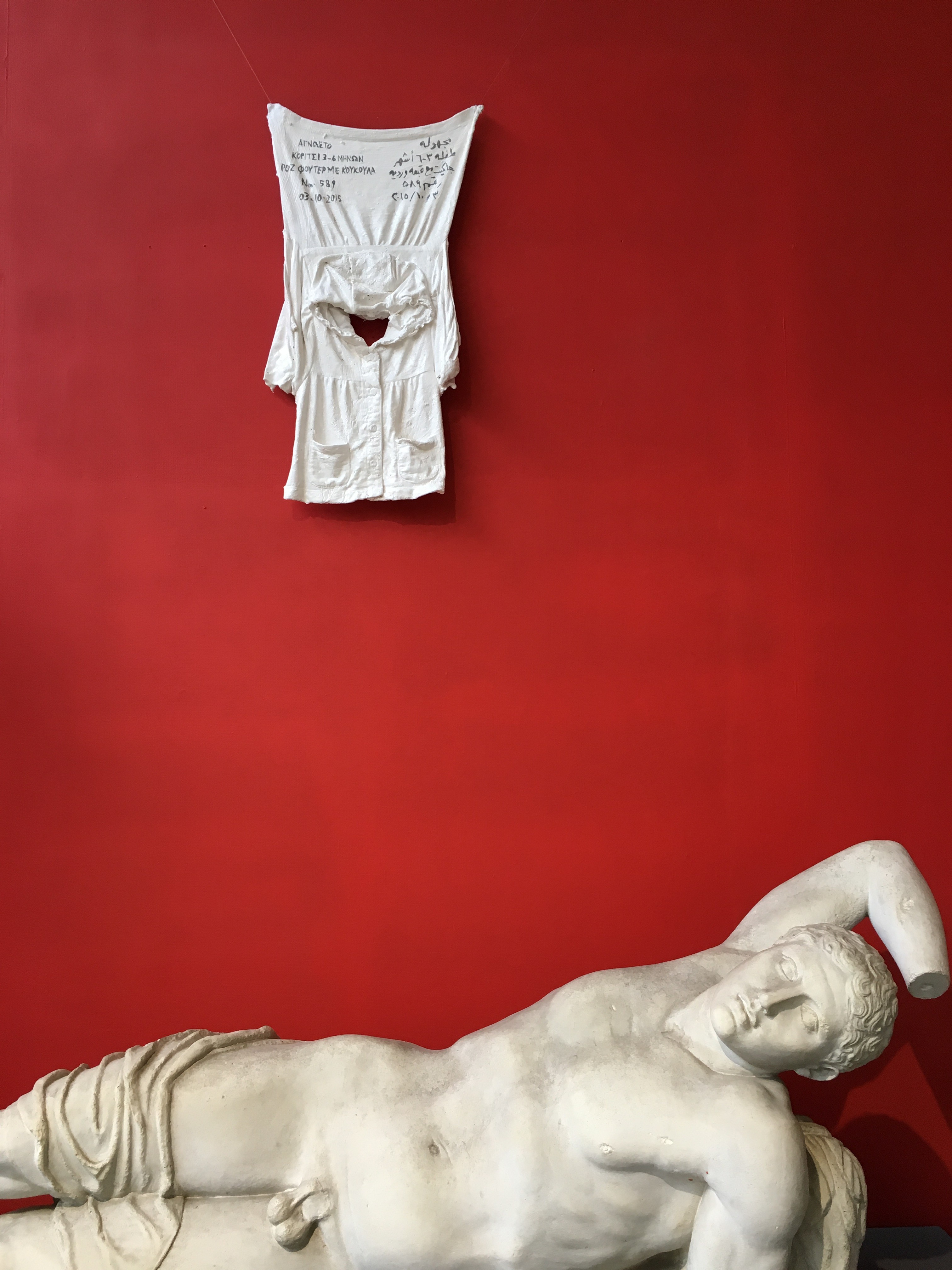 the same sculpture of a reclining naked young man, with plaster clothes hanging above