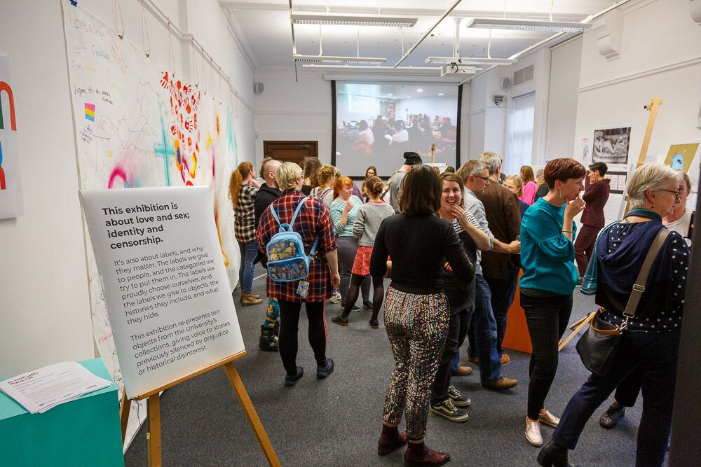 lots of people at a party for the Museum Remix display, with a large information panel in foreground