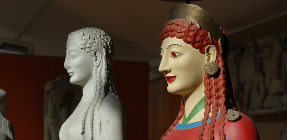 sculpted head of a woman with red hair and a red dress, with unpainted version in background