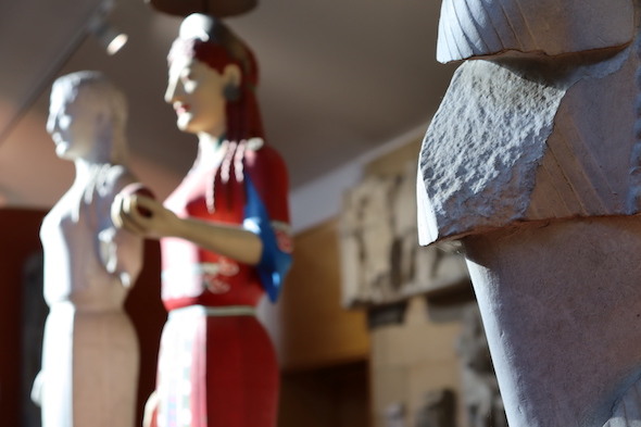 view of unpainted and painted Peplos Kore, out of focus in background