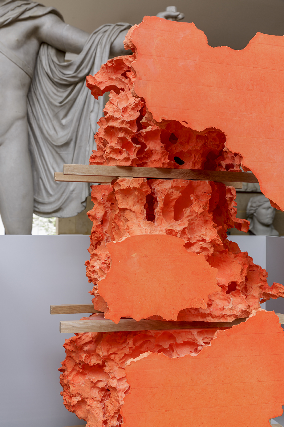 orange mould-made abstract installation in front of plaster cast of a man