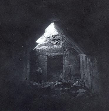 black and white photo of a little local boy seated in a dark tomb interior