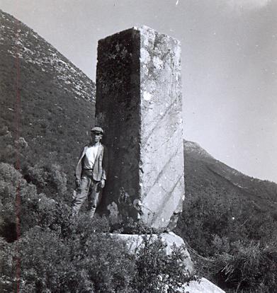 black and white photo of a local young man next to a standing stone