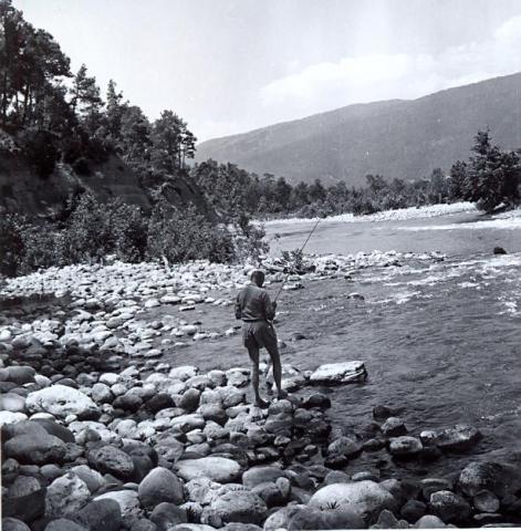 black and white photo of a man fishing, from behind