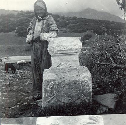 black and white photo of a local Turkish woman in a headscarf standing next to a standing stone