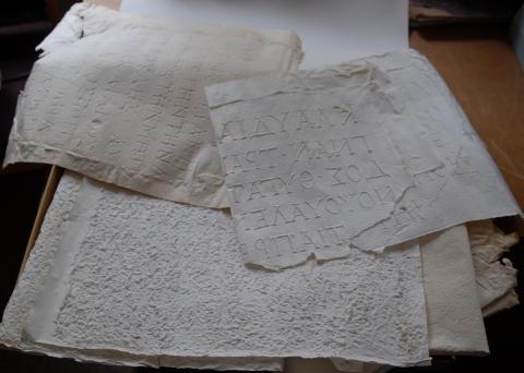 colour photograph of paper imprints of inscriptions (squeezes) on a table