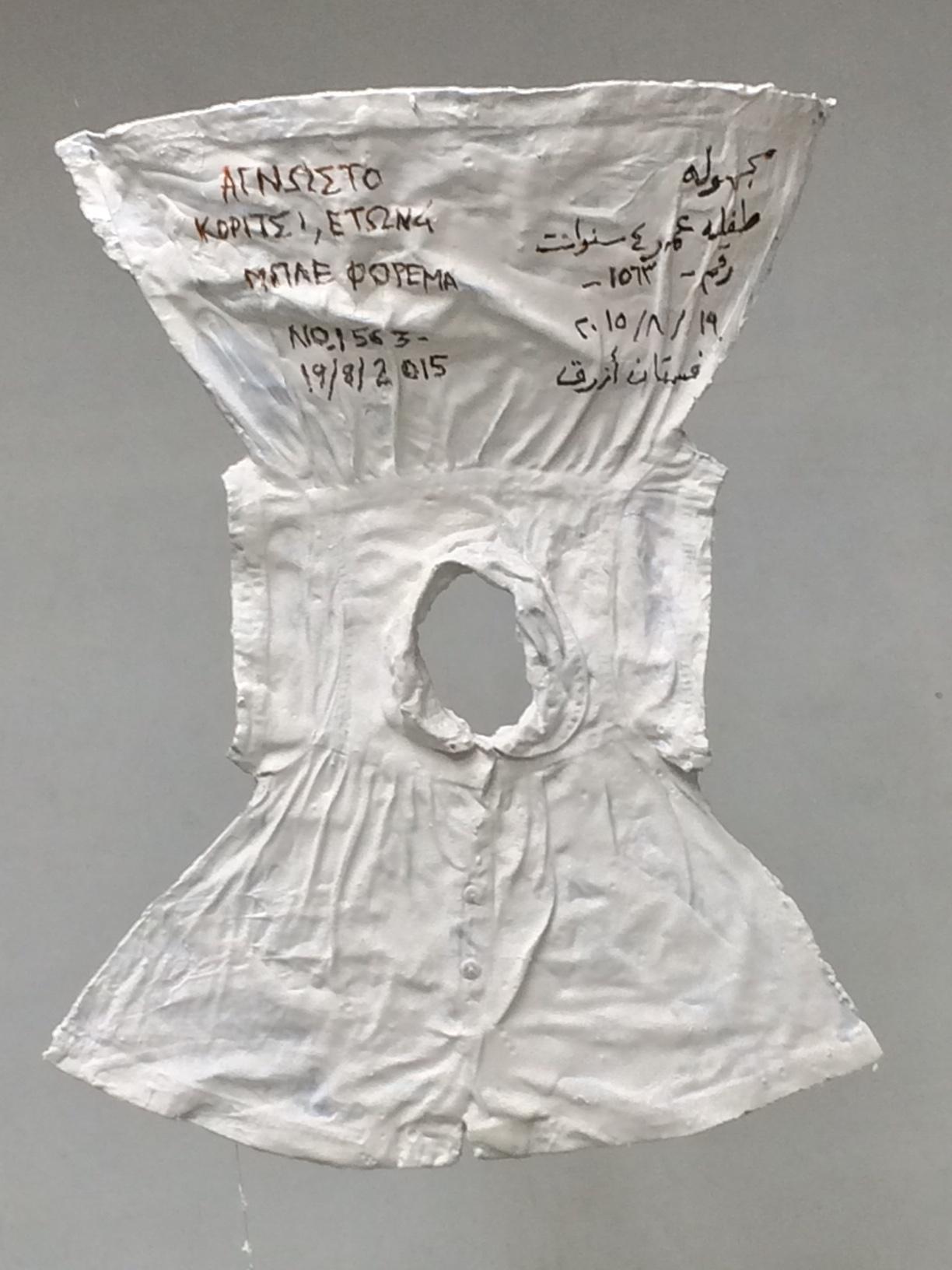 a clothing item which once belonged to a refugee, dipped in plaster and written on