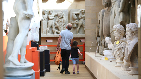 View of grandparent and child walking through gallery of classical casts
