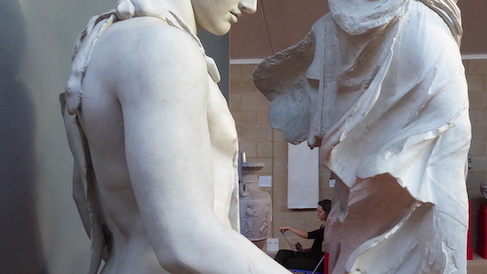 view of plaster casts, with person drawing in the background