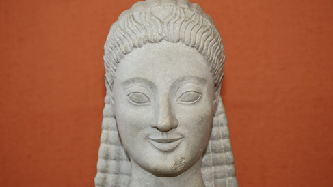 head of an archaic kouros, against an orange background