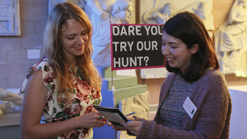 Two women volunteer at an event, smiling broadly