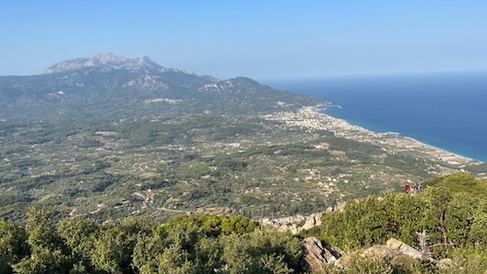 landscape view of island of Samos, with green tree covering central peaks and blue sea in background