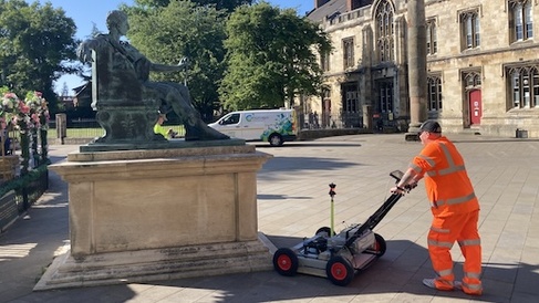 Man in high vis pushing machine next to a monument in York