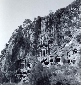 black and white photo of rock-cut tombs/apertures in a hillside