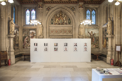 Photographs on display on white wall in ornate room in the Houses of Parliament