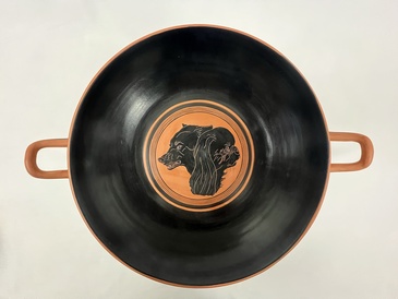 a round black-glaze drinking cup, with two dogs heads in the central circular field