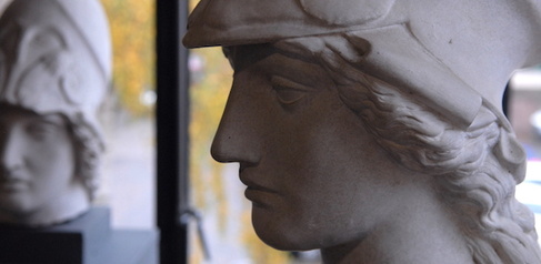 sculpted head of Athena in helmet, with leafy background