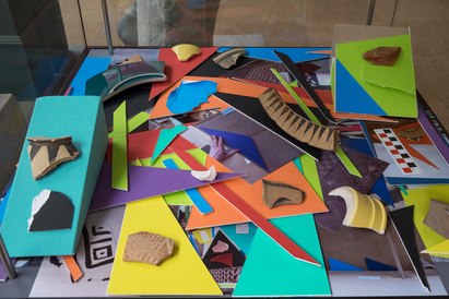 Lots of coloured mountboard shapes layered on top of each other, with sherds displayed on coloured slopes