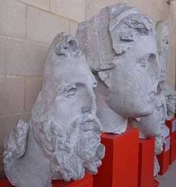 a sculpted head of a bearded man nex to the head of woman, with other heads behind