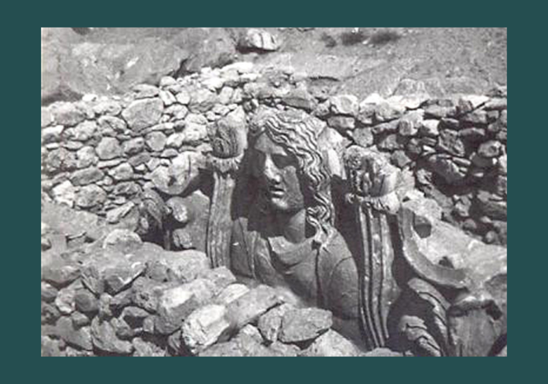 black and white image of a relief sculpture partly hidden by walls/rubble