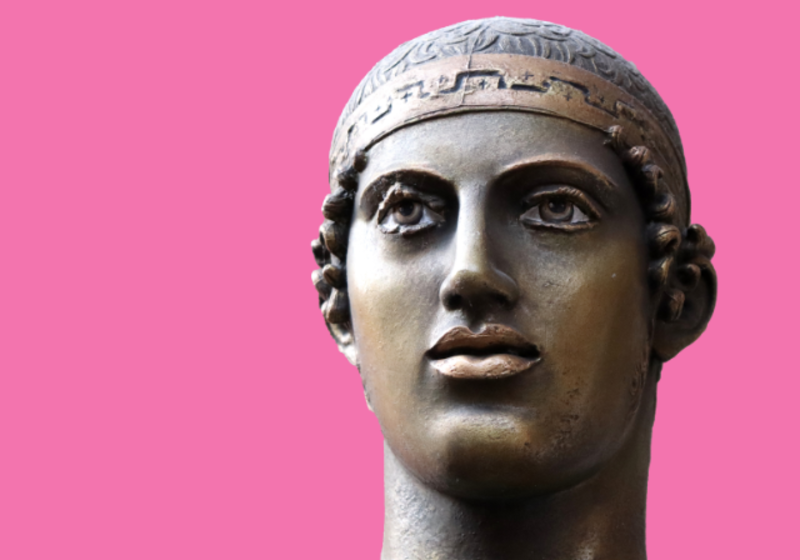 bronze head of a statue on a pink background