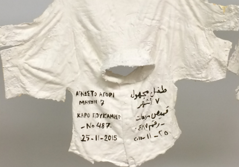 children's top, hanging updside down and dipped in plaster, with words written on it