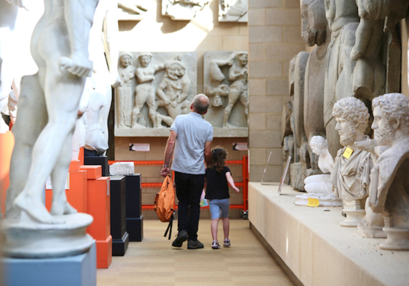 View of grandparent and child walking through gallery of classical casts