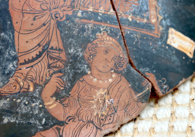 red-figure pottery sherd with crack, well dressed woman on black background