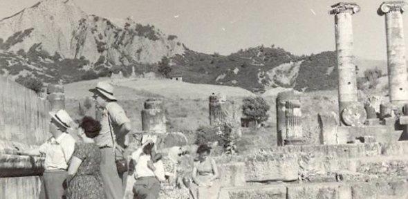 black and white photo of a group of men and women looking at a ruined temple