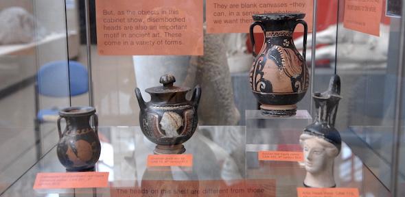 None pots with faces/heads on display in cabinet