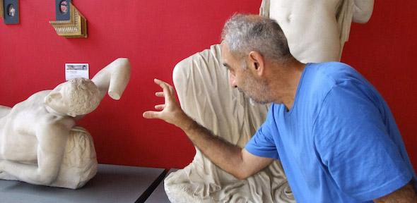 Issam Kourbaj reaches out to one of the dying Niobid statues, against a red wall