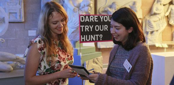Two women volunteer at an event, smiling broadly