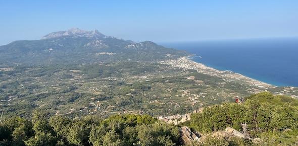 landscape view of island of Samos, with green tree covering central peaks and blue sea in background
