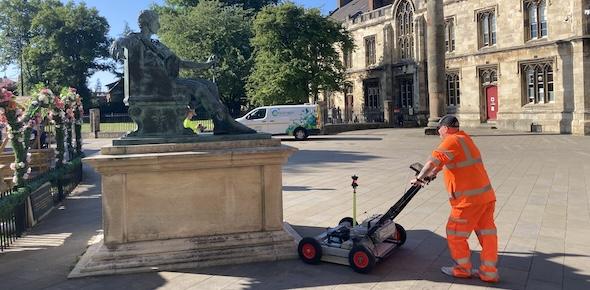 Man in high vis pushing machine next to a monument in York