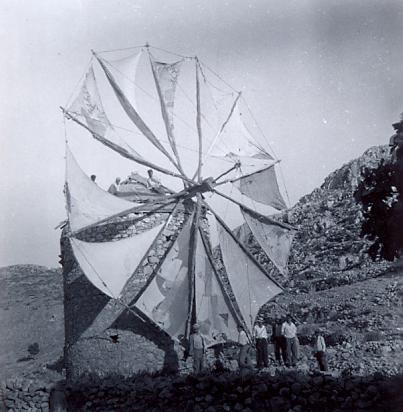 black and white photo of a group of men in front of a windmill