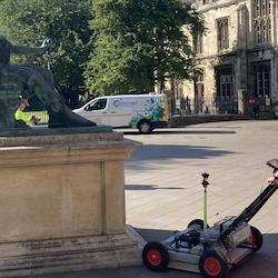 Man in high vis pushing machine next to a monument in York