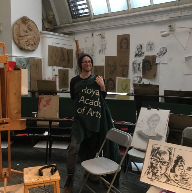 Dominic Blake in an art studio, surrounded by sketches of men and women
