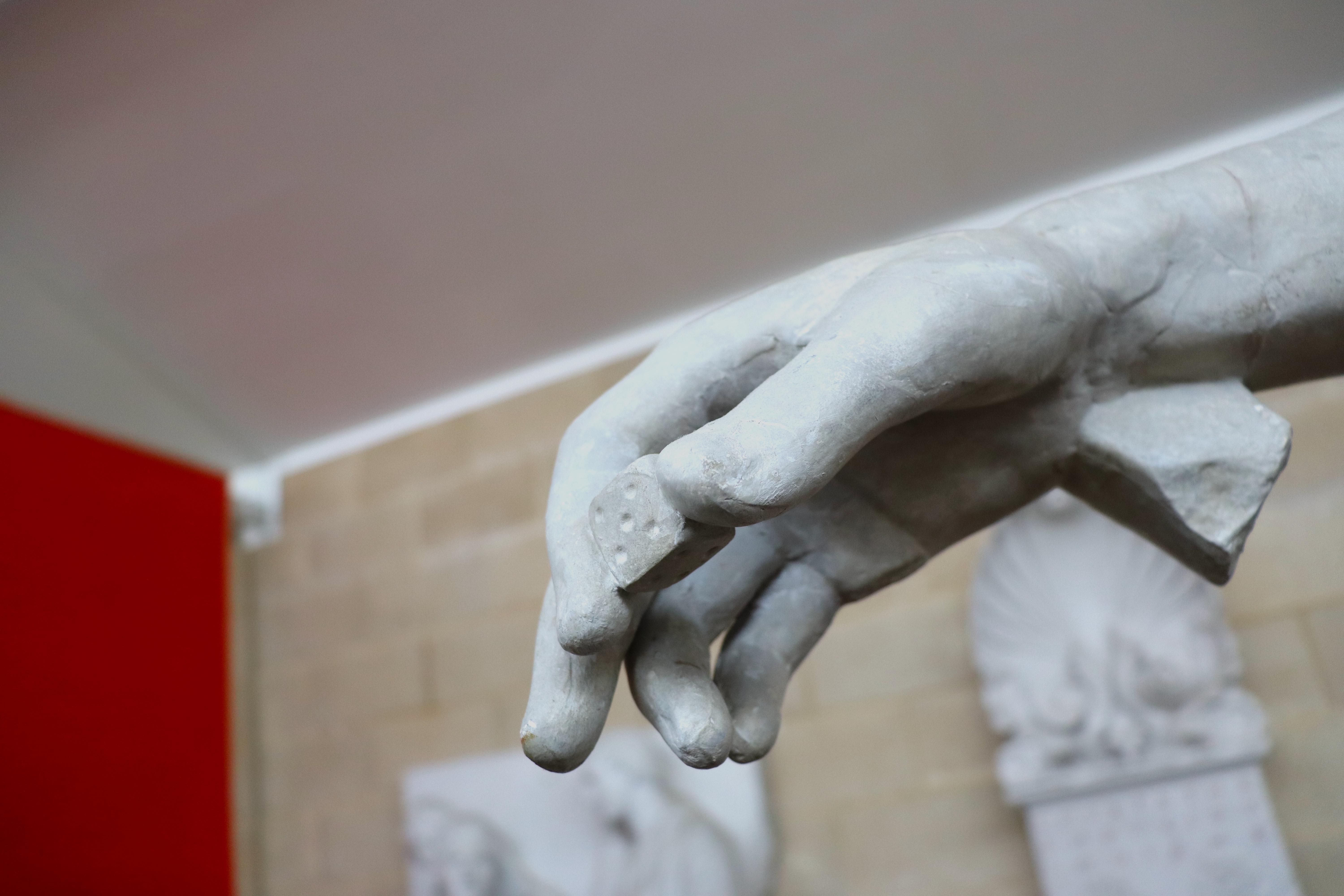Hand of a statue holding a die.