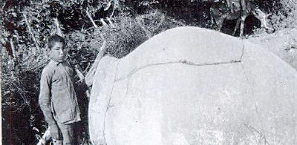 black and white photo of a young Turkish boy next to a large overturned pithos jar