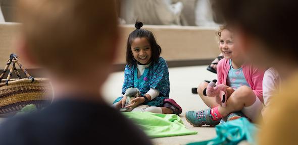 young children in the Museum at an event, holding cuddly toys and laughing