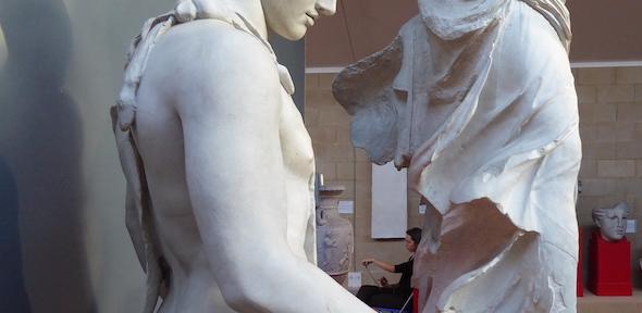 view of plaster casts, with person drawing in the background